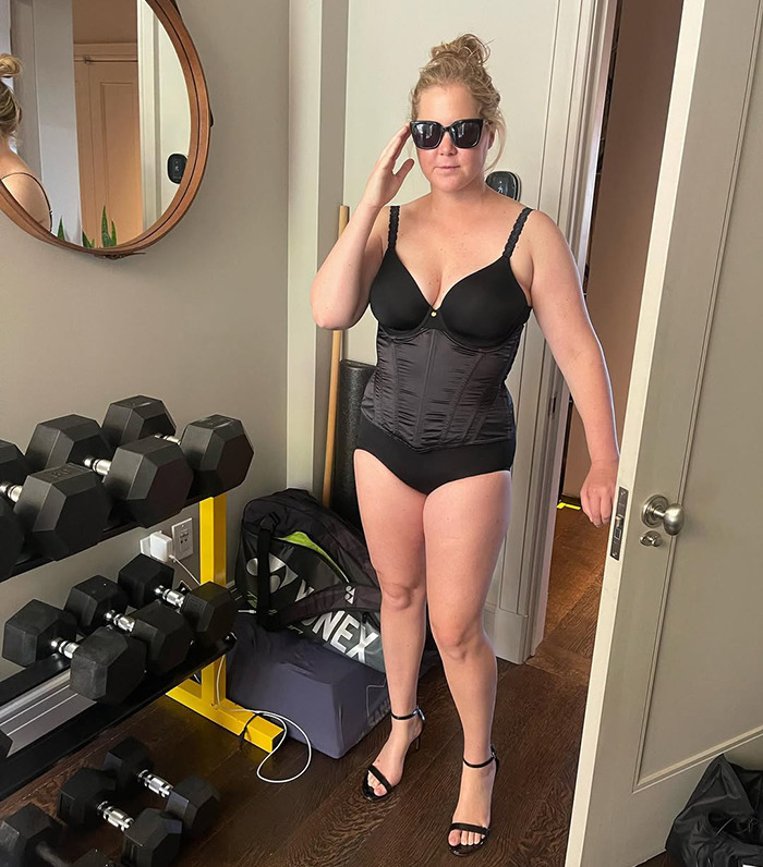 Amy Schumer in sunglasses wearing workout attire in a home gym setting.