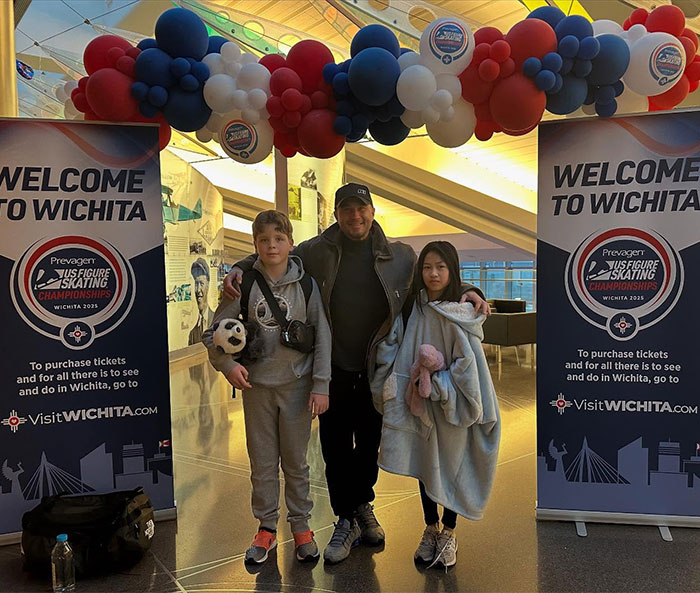 Young ice skating duo with an adult at Wichita event entrance, surrounded by colorful balloons. Young ice skating duo with an adult at Wichita event entrance, surrounded by colorful balloons.