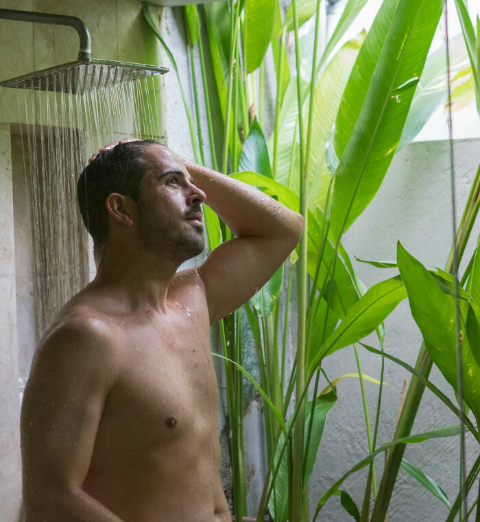 Man enjoying a refreshing shower surrounded by greenery, exemplifying non-s****l attraction.