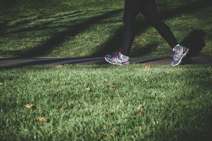 Person walking in park, wearing colorful sneakers, embracing a simple lifestyle.