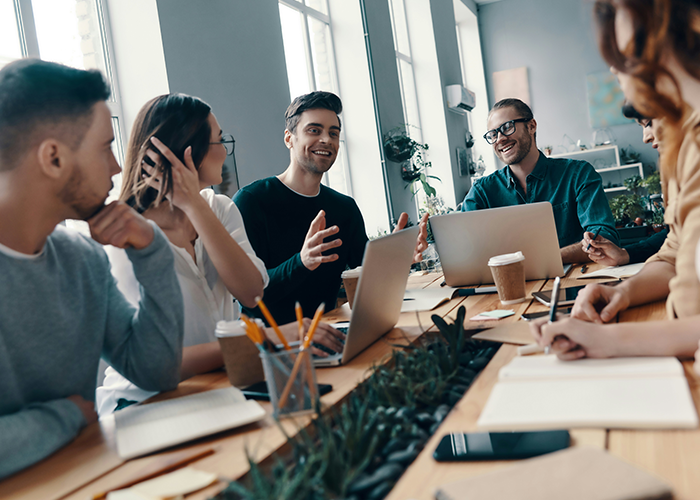People in a meeting, discussing business topics with laptops and notebooks on the table.