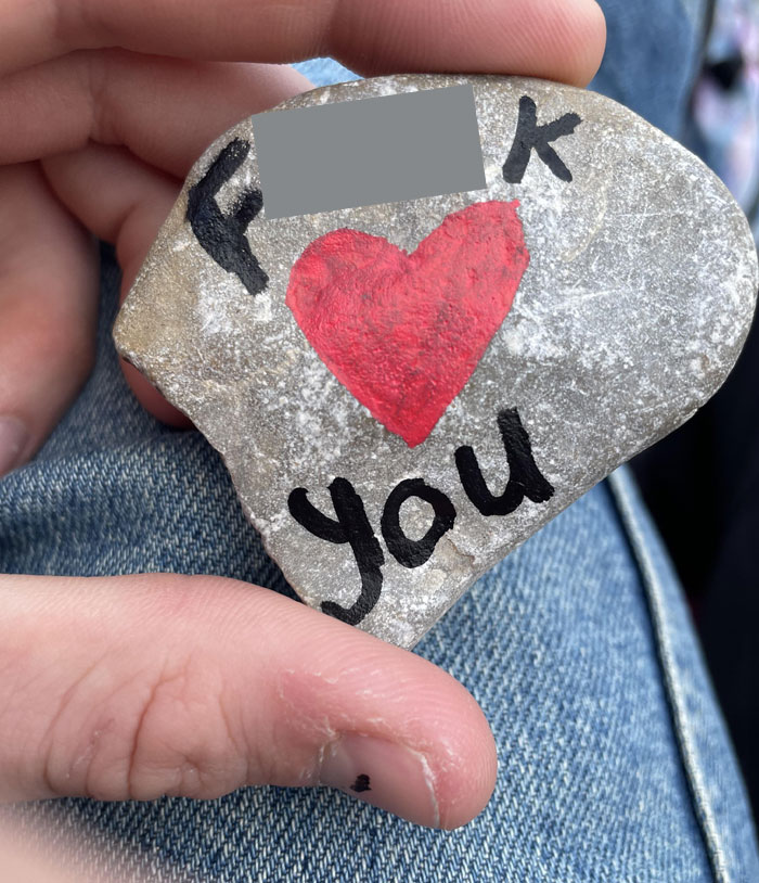 A rock with a red heart and text in a person's hand symbolizing awkward date moments.