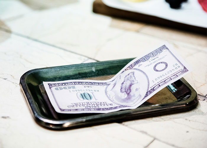 100-dollar bill on a restaurant tip tray, related to customer tipping 10% for service. 100-dollar bill on a restaurant tip tray, related to customer tipping 10% for service.