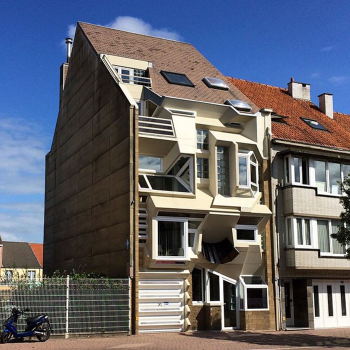Hilariously bad house with a distorted facade, located in a Belgian neighborhood under a clear blue sky.