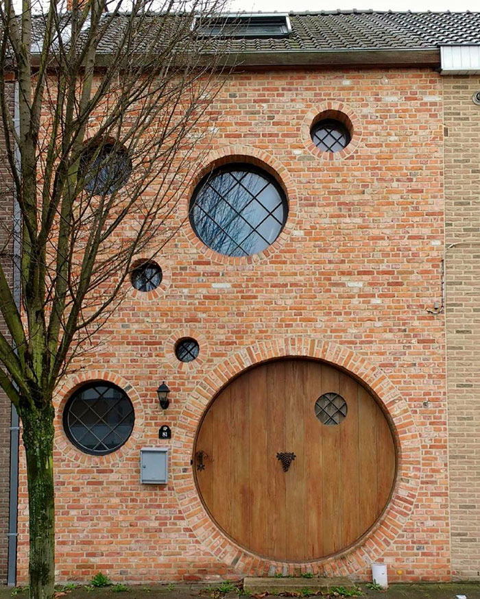 Unconventional brick house with circular windows and door, exemplifying humorously bad architecture.