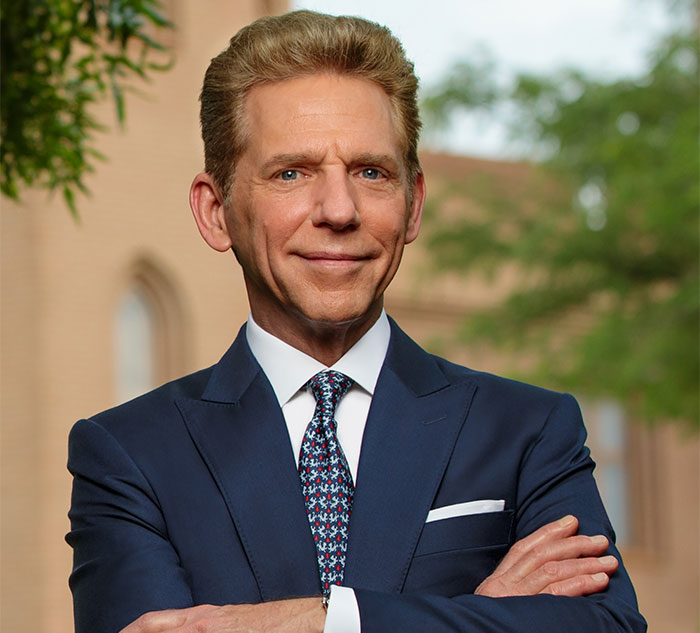 A man in a blue suit and patterned tie standing outdoors, representing celebrity secrets.