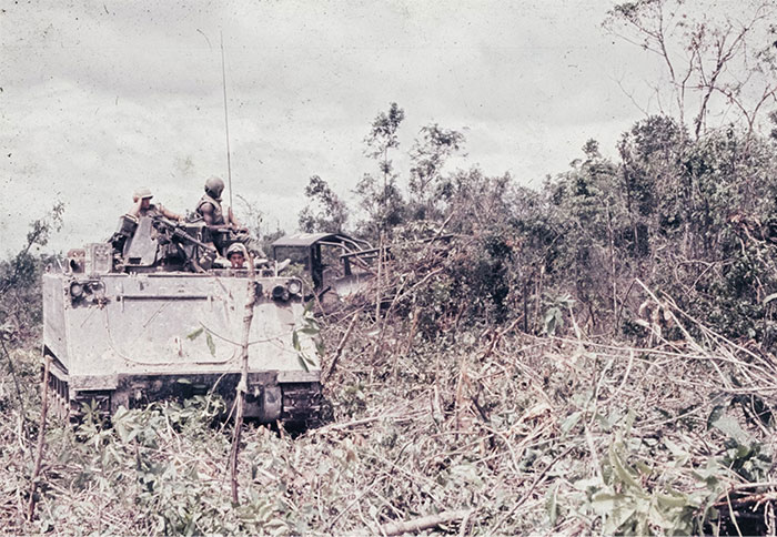 Military vehicle moving through dense forest, illustrating historical financial waste.