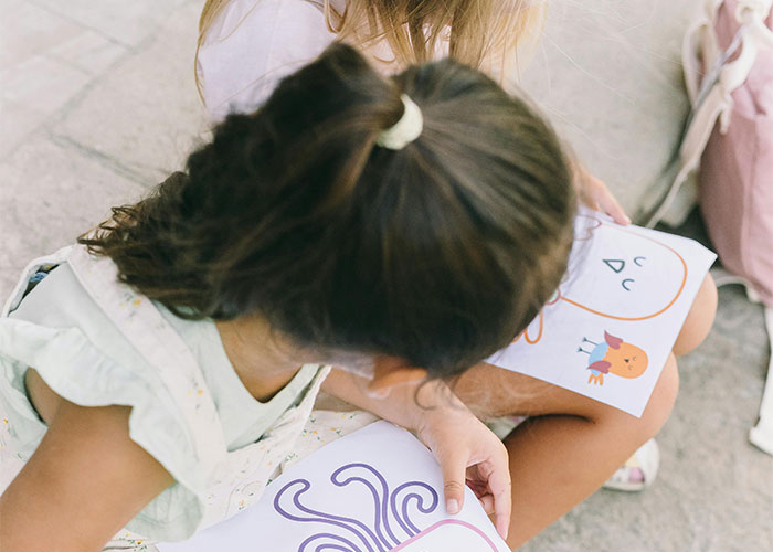 Children engaged in reading, reflecting on unsolved mysteries from their countries in an outdoor setting.