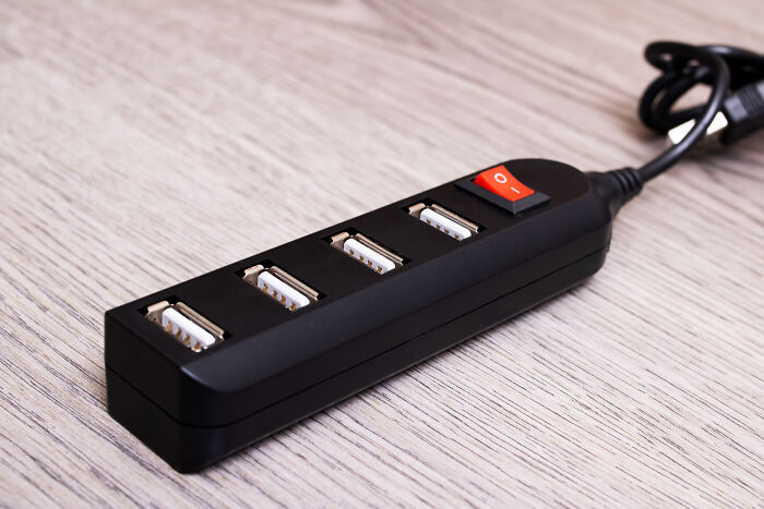 USB hub with four ports and a power switch on a wooden table, highlighting a space-saving purchase.