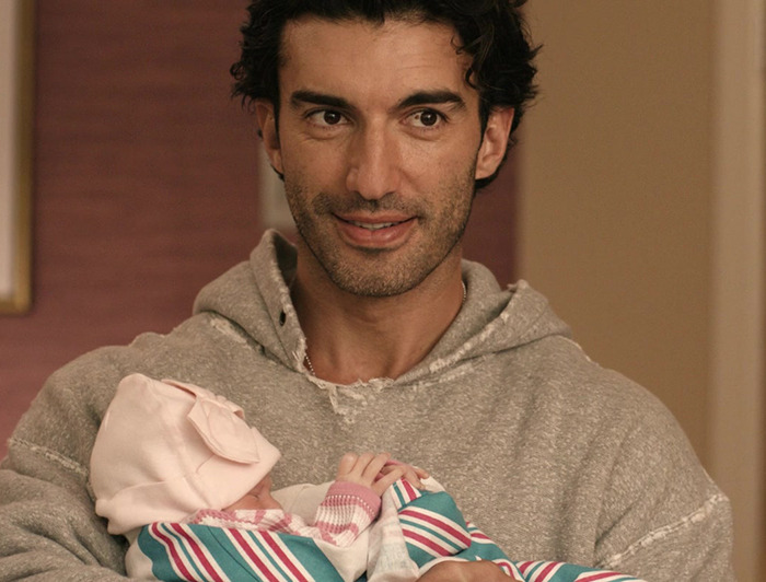 Justin Baldoni in a gray hoodie holding a baby from It Ends With Us. Justin Baldoni in a gray hoodie holding a baby from It Ends With Us.
