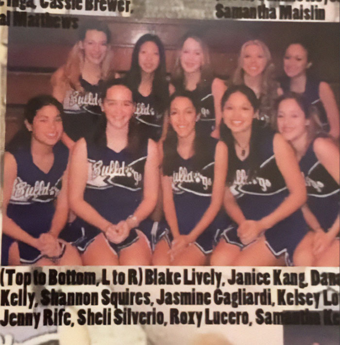 High school cheerleading squad with Blake Lively in uniform, seated on bleachers.