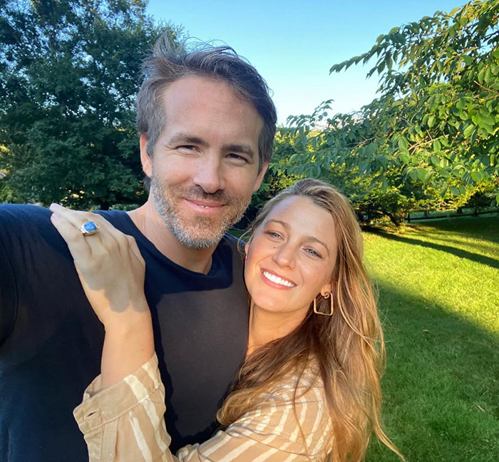 Blake Lively and husband Ryan Reynolds smiling for a picture outdoors.