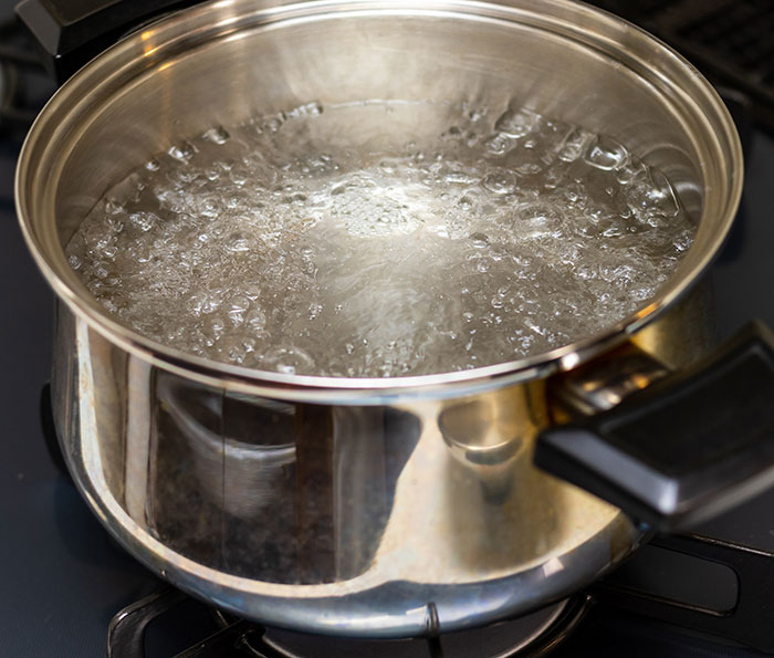 Boiling water in a metal pot on a stove, related to a sleepover prank incident.