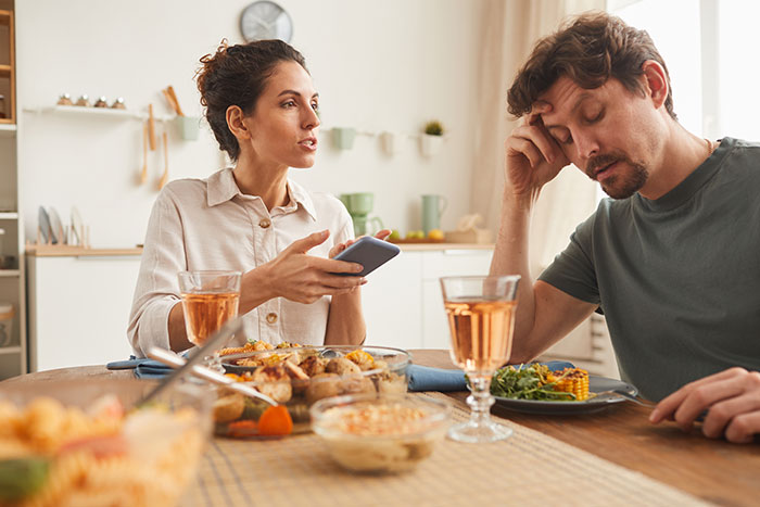Woman discussing money issues with boyfriend over dinner, appearing frustrated about a Europe trip.