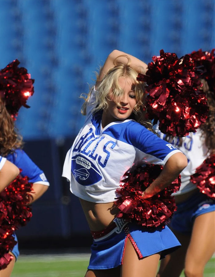 Buffalo Bills cheerleader performing a routine in uniform on the field. Buffalo Bills cheerleader performing a routine in uniform on the field.