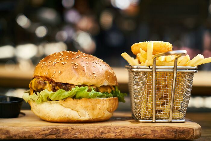 Burger and fries on a wooden board, showcasing clever tips for living cheap yet comfortably.