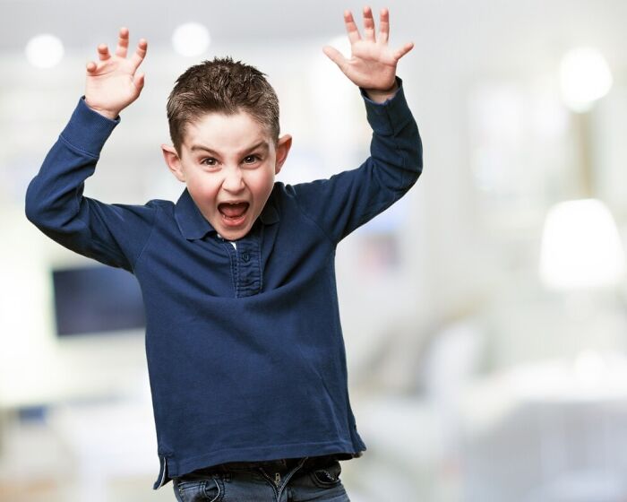 Child making a silly expression with raised hands, symbolizing absurd things kids do in school.