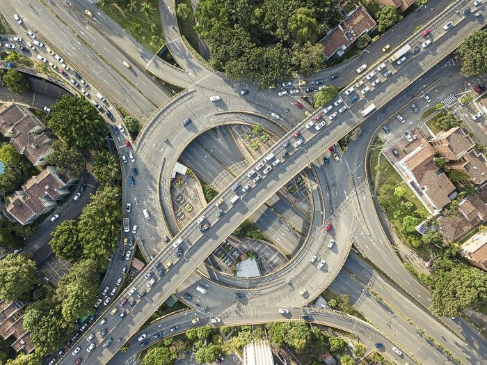 Aerial view of a complex highway interchange surrounded by trees and buildings, illustrating facts from history.