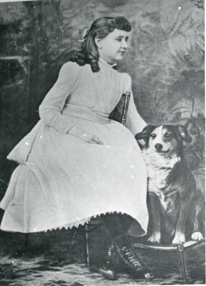Black and white photo of a girl in vintage dress sitting with a dog, illustrating facts about history not taught in school.