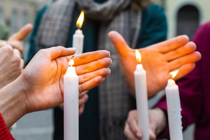Hands warming by candle flames during an outdoor gathering illustrating facts you weren’t taught in school history.