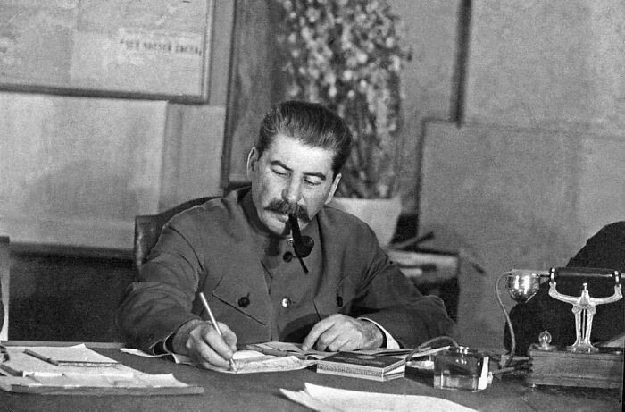Historical figure with pipe writing at desk surrounded by papers, illustrating facts about history not taught in school.