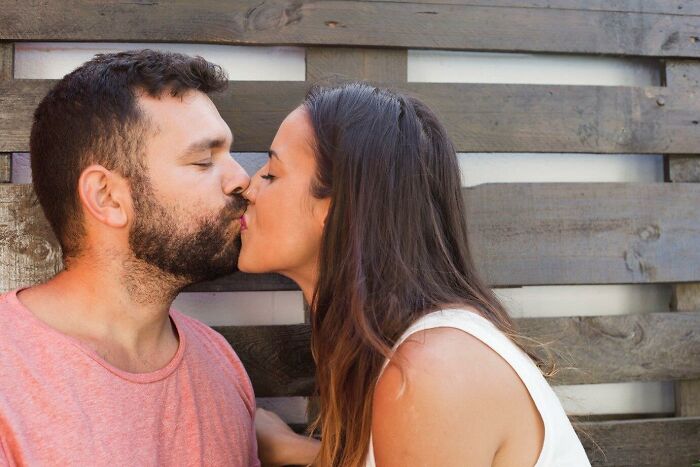 Couple kissing in front of a wooden fence, woman concerned about neighbor only greeting her husband.