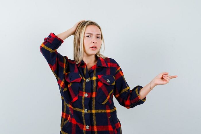 Confused woman in a plaid shirt questioning her neighbor's behavior.
