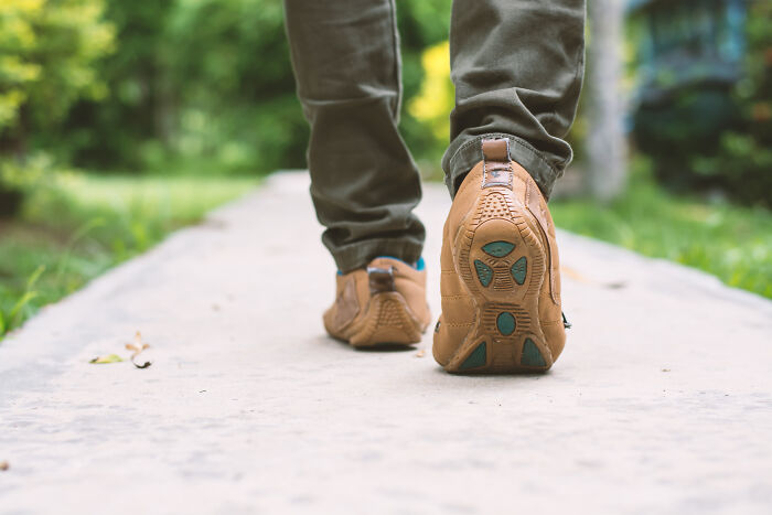 Close-up of a person walking on a path in brown shoes, highlighting how buying these items improved their life.