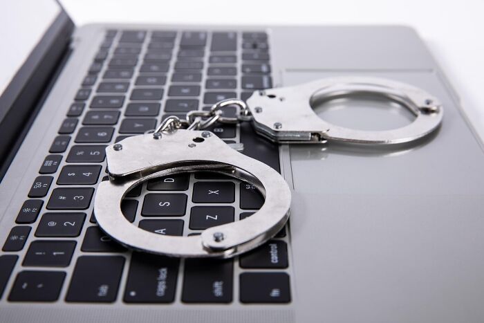 Handcuffs resting on a laptop keyboard, symbolizing constraints in a digital context, related to "weird ones."