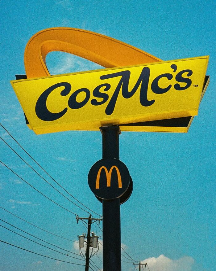 Cosmic McDonald's sign under a clear blue sky with power lines in the background.