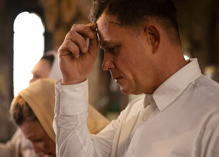 Man in a white shirt appearing deep in thought, portraying the tension of horror movie-worthy family secrets.
