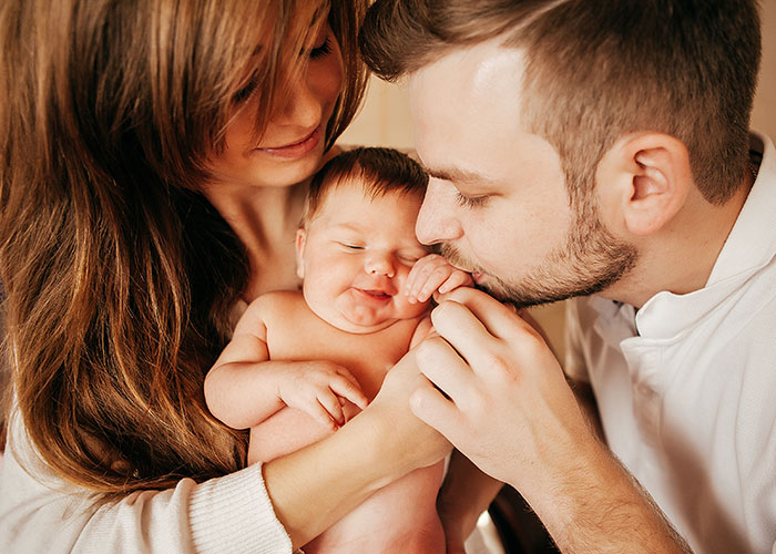 Pareja cariñosa con bebé recién nacido, ilustrando secretos familiares.