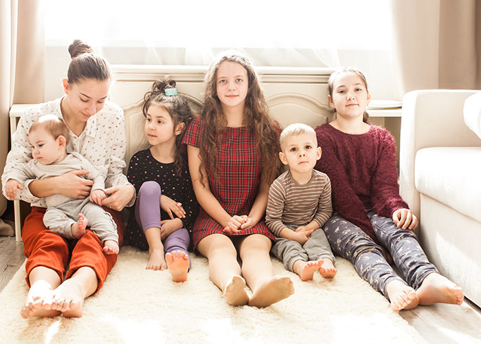 A family group sitting on a carpet in a bright room, illustrating horror movie-worthy family secrets concept.
