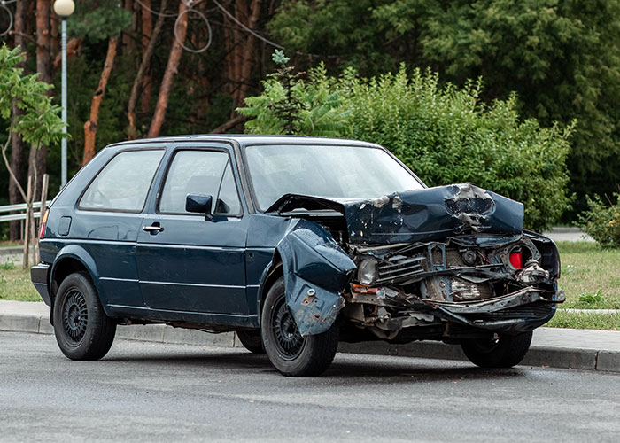 Damaged black car with front-end collision parked by the roadside, illustrating car accident horror movie-worthy family secrets.