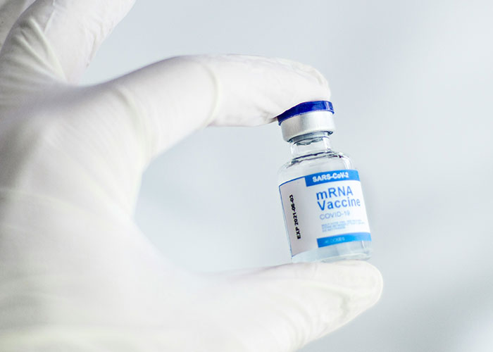 Gloved hand holding an mRNA vaccine vial, highlighting unsettling medical facts.