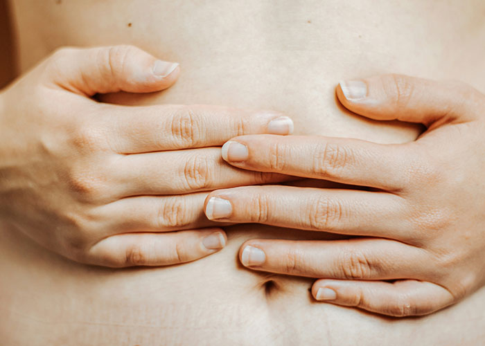 Hands placed on a bare stomach, illustrating unsettling medical facts about human anatomy.