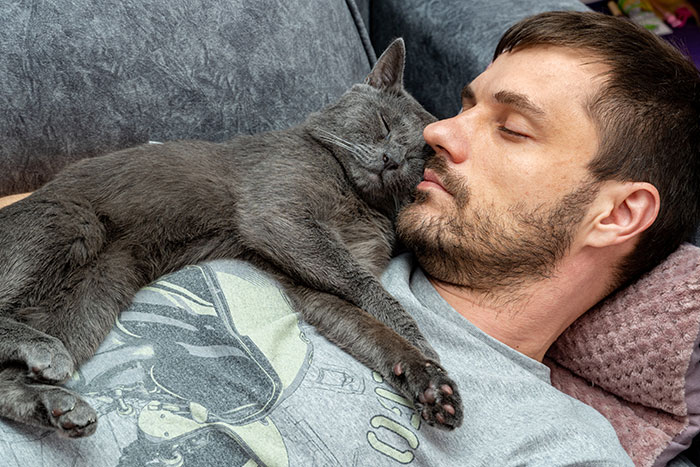 Man cuddling with a cat on the couch, showcasing adorable moments with partners.
