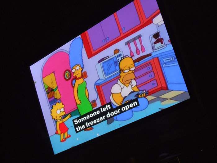 TV screen showing animated family in kitchen with freezer door left open.