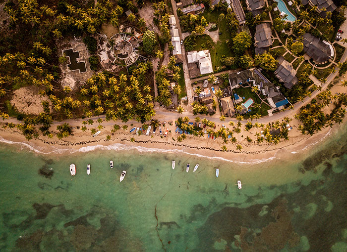 Aerial view of a tropical beach resort, lined with palm trees, captures a serene vacation setting. Aerial view of a tropical beach resort, lined with palm trees, captures a serene vacation setting.