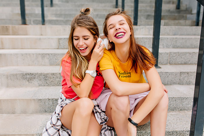 Two teens sitting on stairs, laughing and enjoying a vacation moment. Two teens sitting on stairs, laughing and enjoying a vacation moment.