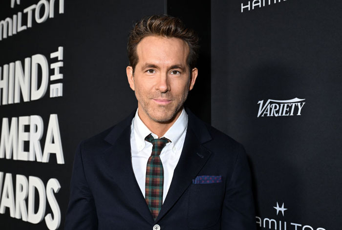 Actor Ryan Reynolds at an award event, wearing a suit and tie, related to Deadpool cast in part 3.