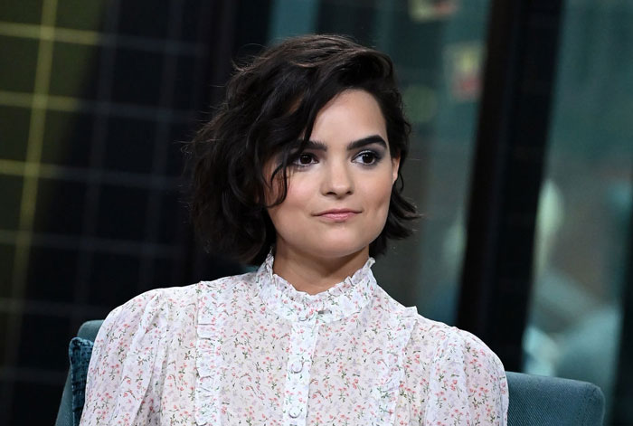 Actress Brianna Hildebrand from Deadpool cast in interview, wearing a floral blouse with short hair, smiling slightly.