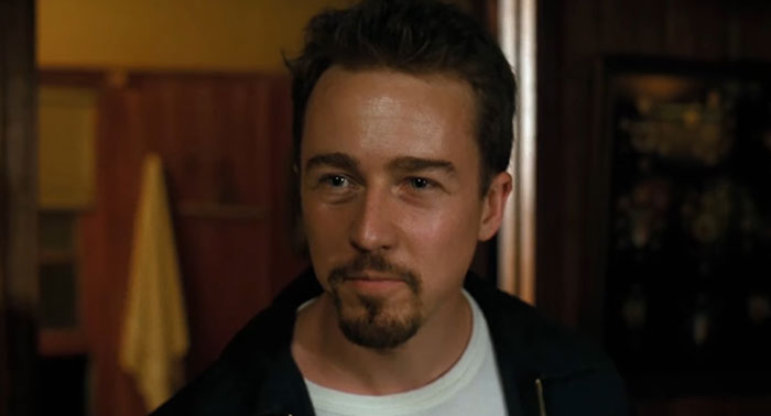 Scene from a movie with a sad and depressing ending; a man with short hair and a goatee looks intently ahead.
