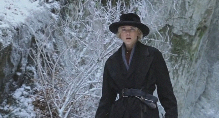 A woman in a black coat and hat stands in a snowy, barren landscape, evoking a sad and depressing movie ending mood.