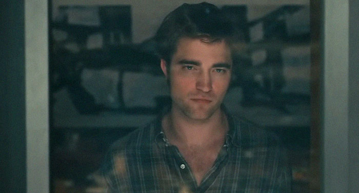 A man with a serious expression looks through a window, evoking a sad and depressing movie ending.