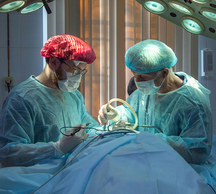 Surgeons in operating room wearing surgical gowns and caps, performing a medical procedure related to breast reduction. Surgeons in operating room wearing surgical gowns and caps, performing a medical procedure related to breast reduction.