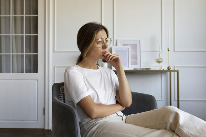 A woman sitting thoughtfully in a modern living room, symbolizing signs of intelligence.
