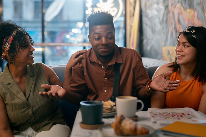 Three friends having a lively discussion in a cafe, illustrating signs of intelligence through curiosity and engagement.