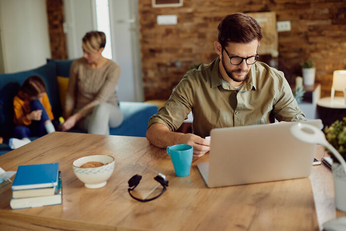 Man in glasses using a laptop at a wooden table, focusing on signs of intelligence.