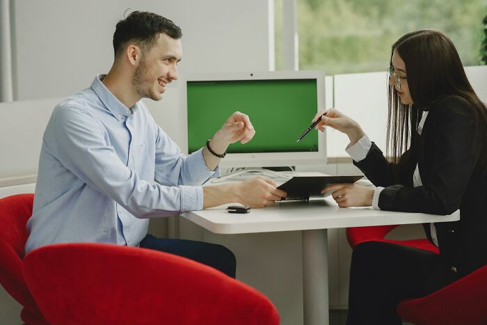 Two people in a meeting, discussing ideas, a sign of intelligence; both are seated at a table with a tablet and laptop.